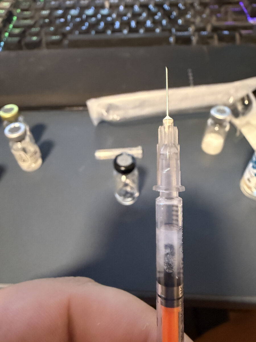 Close-up of the same syringe: white, flocculent precipitate suspended in the fluid