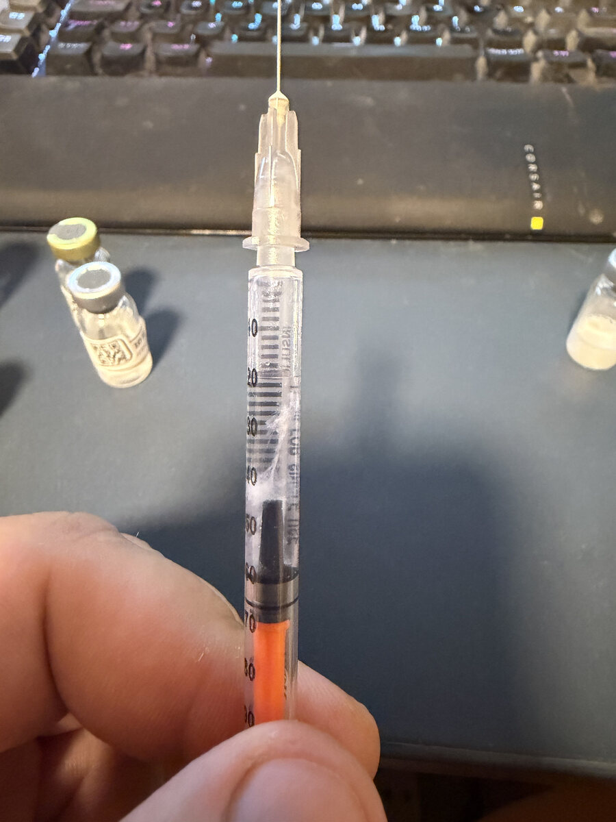 Insulin syringe with clearly visible white strands and streaks in the barrel after several peptides were combined